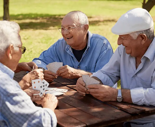 Three older men sitting at a table playing cards.