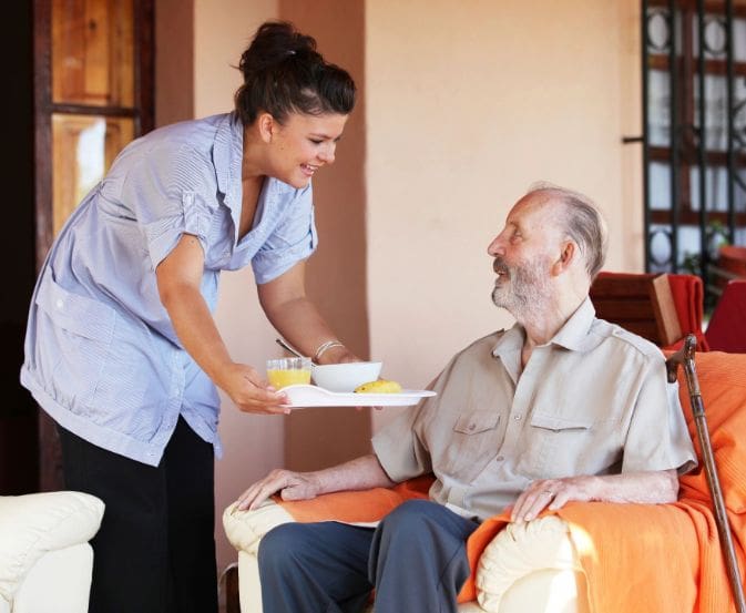 A woman serving food to an older man.