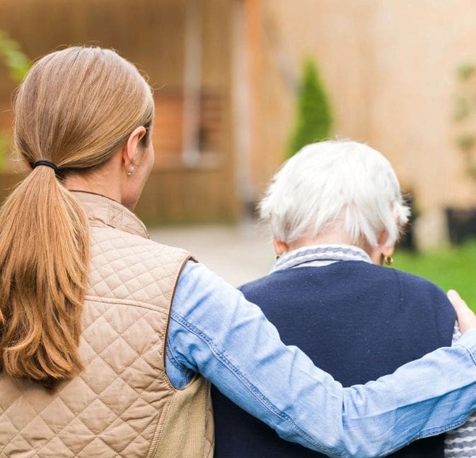 A woman and an older man are hugging outside.